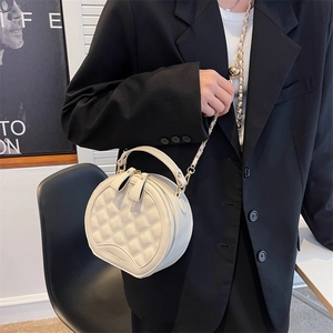 Petit sac rond blanc matelassé avec bandoulière chaîne porté sur une veste noire