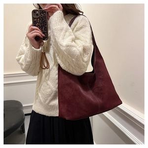 Shoulder shot of a burgundy matte bucket bag with white contrast stitching detail