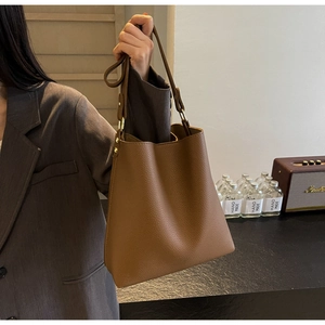 Detailed texture of brown lychee grain leather tote bag with elegant metal hardware buckle
