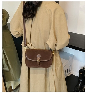 Detail of deep brown frosted leather shoulder bag with vintage gold buckle on trench coat
