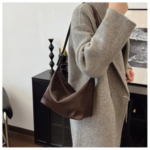 Detail of dark brown leather Hobo bag with adjustable strap worn with a grey wool coat