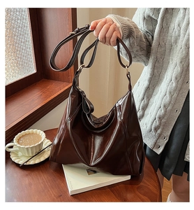 Détail du grand sac hobo en cuir marron foncé sur une table de café en bois avec finitions dorées