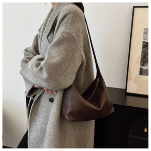 Detail of a dark brown vintage hobo shoulder bag worn by a model in a minimal setting