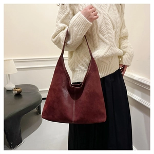 Detail of burgundy large tote bag with white contrast stitching and matte texture