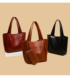 Three minimalist large capacity tote bags in red, brown, and black colors on pedestals