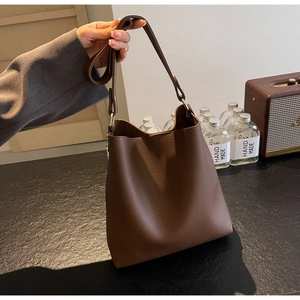 Close-up detail of premium brown pebble grain leather bucket bag with golden hardware