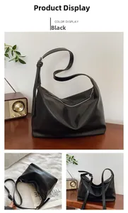 Detail view of a black soft leather hobo bag with silver zipper on a wooden table