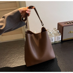 Detail of premium brown pebble grain leather bucket bag with soft texture and shoulder strap