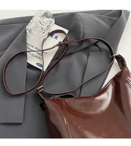 Détail de la bandoulière réglable avec boucle dorée sur un sac hobo en cuir marron foncé