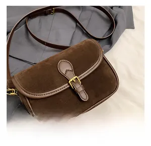 Close-up of retro brown frosted suede shoulder bag with golden buckle and strap details
