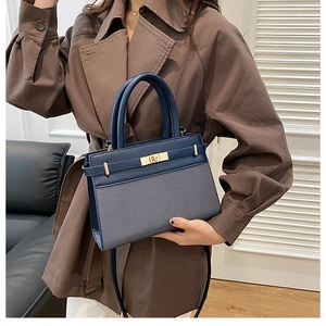 Detail view of the blue paneled handbag with gold twist lock and fine leather shoulder strap