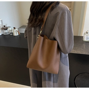Brown lychee leather tote bag with gold hardware shown in a minimalist cafe setting