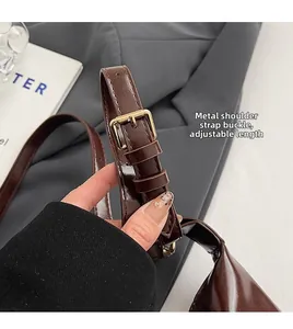 Détail de la bandoulière réglable en cuir brillant avec boucle en métal doré du sac