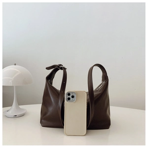 Detailed view of brown faux leather shoulder bag with phone for scale comparison