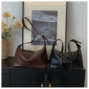 Detail of vintage matte leather tote bags in black and dark brown with adjustable straps