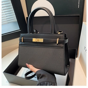 Detail of black leather and fabric handbag featuring a luxury gold clasp and metal hardware