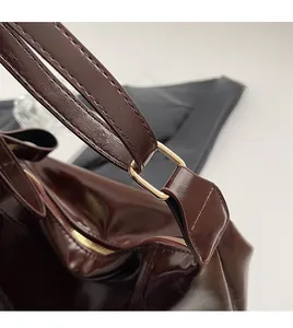 Détail du sac cabas en cuir brillant bordeaux avec boucle en métal doré élégante