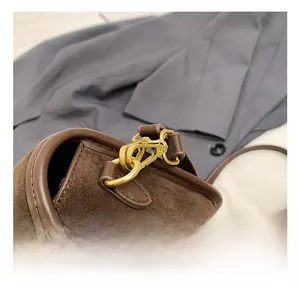 Detail of premium gold-tone metal hook and dark brown suede texture on a square bag