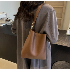 Detailed view of brown litchi grain leather tote bag with elegant gold hardware buckles