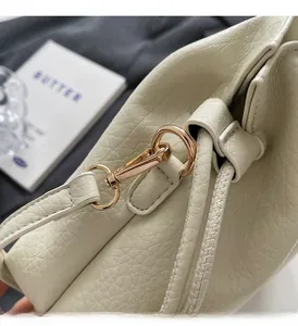 Gros plan sur le sac en cuir crème à motif litchi avec des ferrures métalliques dorées