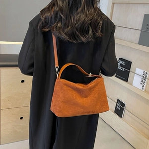 Retro orange suede half-moon shoulder bag shown on model in minimalist interior