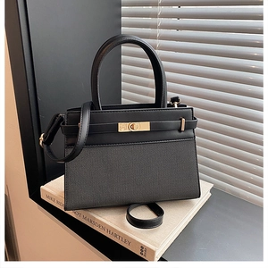 Detail of black leather and fabric patchwork handbag with golden hardware and top handle