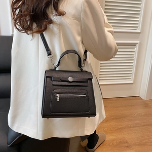 Elegant black lychee leather kelly bag with top handle and adjustable shoulder strap