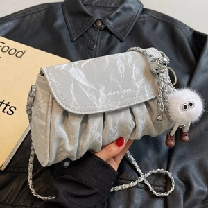 Sac bandoulière plissé argenté avec chaîne et breloque peluche sur fond en cuir noir