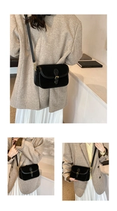 Close-up of black matte square bag with vintage metal buckle and thin leather strap