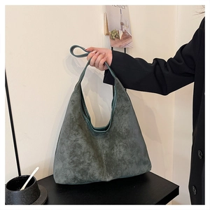 Detail of dark green suede tote with visible vertical stitching and matte texture