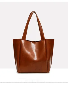 Close-up of the glossy dark brown faux leather texture on a spacious tote handbag