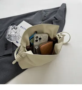Vue de dessus du sac bourse crème montrant l'intérieur spacieux avec téléphone et portefeuille