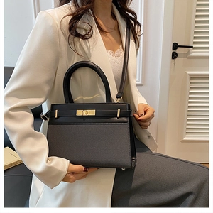 Detail of black leather handbag featuring gold twist lock and textured surface design