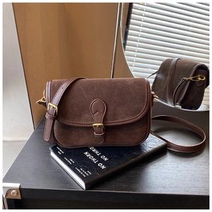 Macro detail of dark brown matte suede shoulder bag with golden metal buckle and stitching