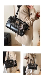 Detail of black glossy leather tote bag with front zipper and metal bible charm