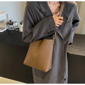 Detailed close-up of brown pebbled leather bucket bag with gold metal hardware