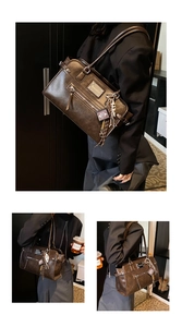 Detail of dark brown vintage tote bag with metal plaque and book charm accessory