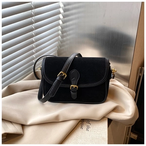 Macro detail of black suede shoulder bag featuring vintage gold buckle and fine texture