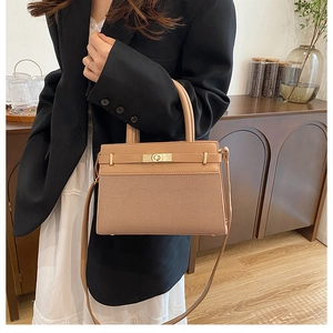 Detailed view of light brown crossbody bag with woven texture and gold clasp on a model