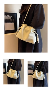 Détail du sac seau crème avec lettrage doré et bandoulière délicate en gros plan