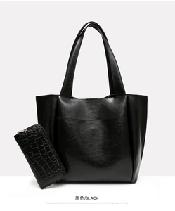 Detail view of large black tote bag paired with matching crocodile embossed zipper wallet