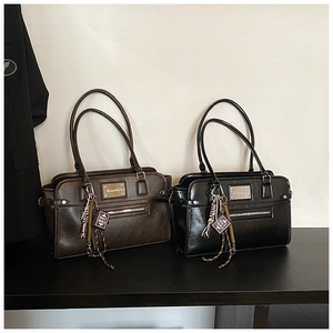 Detail view of black and brown matte handbags with vintage metal plates and bible charms