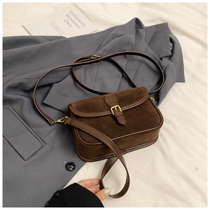 Detail of retro dark brown saddle bag featuring suede texture and gold buckle accents
