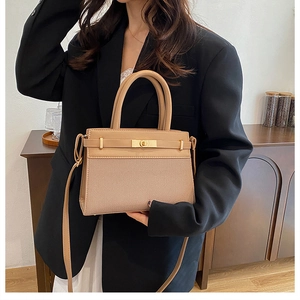 Close-up of khaki satchel with golden twist lock and textured fabric detail on a model