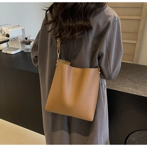 Brown litchi grain tote bag shown worn over the shoulder in a stylish cafe setting