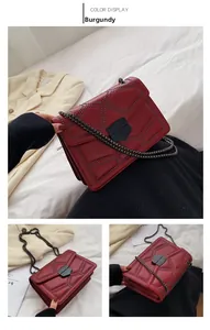Detail of burgundy chain bag with black studs in diamond pattern and metal lock