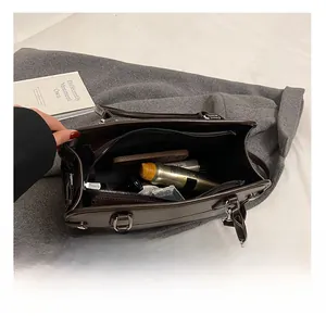 Detail view of large interior storage in brown leather tote showing various personal items