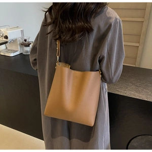 Detailed texture of brown lychee grain leather on a large capacity shoulder bucket bag