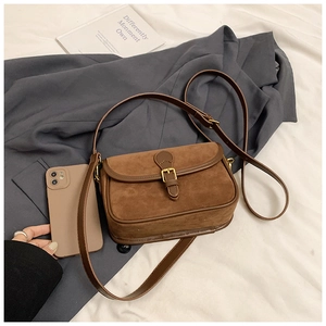 Close-up of caramel brown suede texture on a vintage square bag with metal buckle