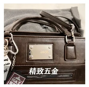 Detailed close-up of dark brown vintage faux leather handbag with metallic logo and zipper